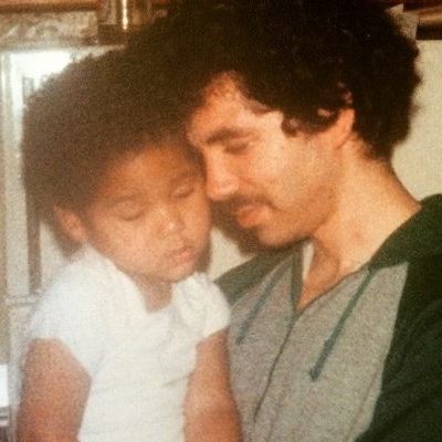 Joel is holding the small Jussie while touching their heads with closed eyes.